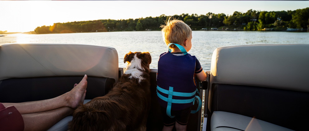 A young boy and his dog enjoying a boat ride on a lake