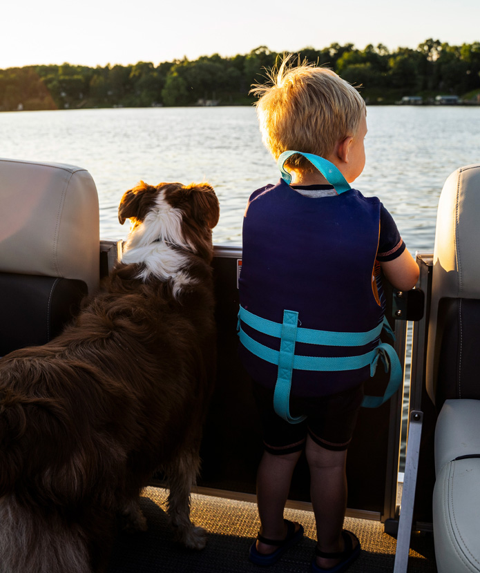 A young boy and his dog enjoying a boat ride on a lake