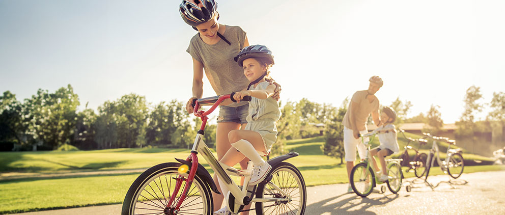 A family out for a bicycle ride wearing protective equipment.