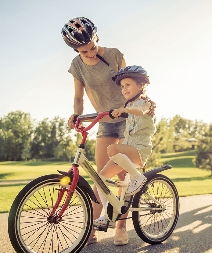 A family out for a bicycle ride wearing protective equipment.