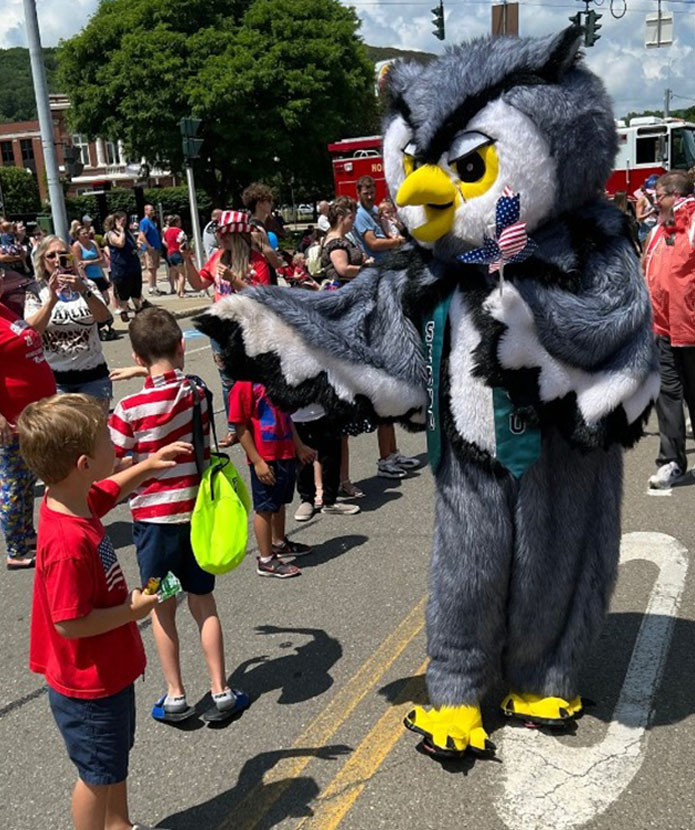 Smarty the Owl handing out American flags at a parade.