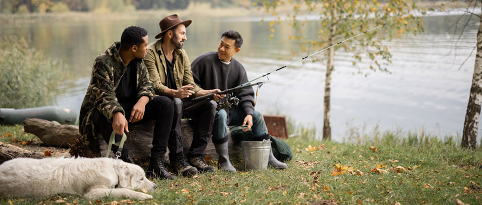 Three men and a dog fishing by a lake