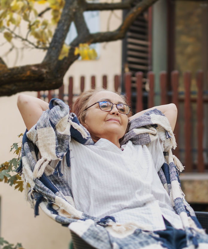 Woman relaxing in a chair next to her front porch