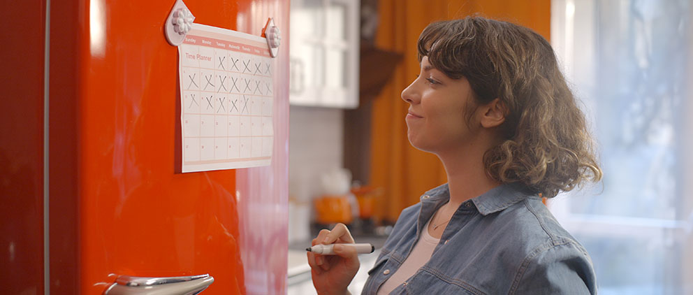 Someone updating a calendar she has posted on her refrigerator door