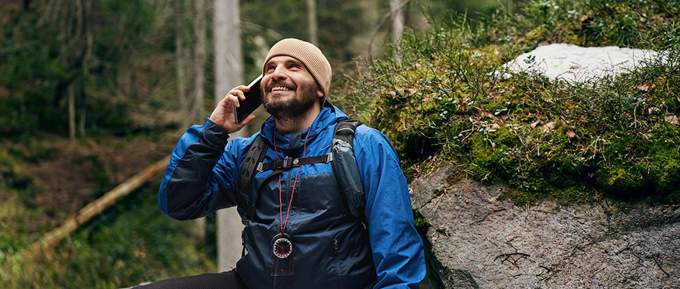 A man checking his account balance using telephone teller while hiking in the woods