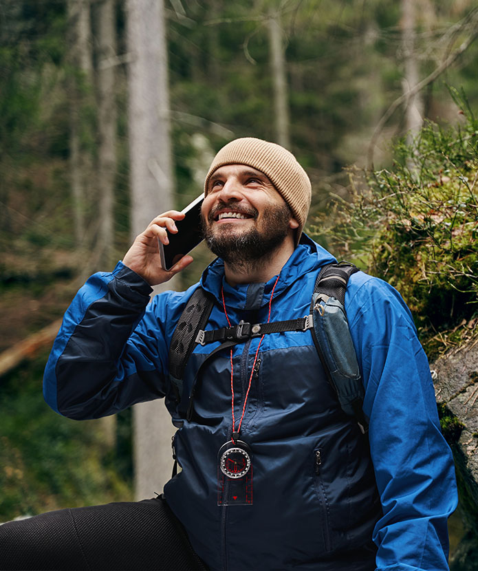 A man checking his account balance using telephone teller while hiking in the woods